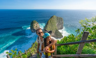 Happy multiracial couple standing above Kelingking beach, enjoying the view and taking selfies..jpg