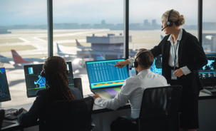 air traffic controllers looking at screens in an airport's air traffic control tower.