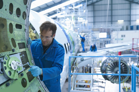 Aircraft engineer fixing a commercial aircraft door inside a hangar