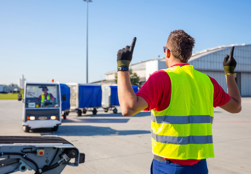 Ground handling person guiding baggage carts to belt-loader